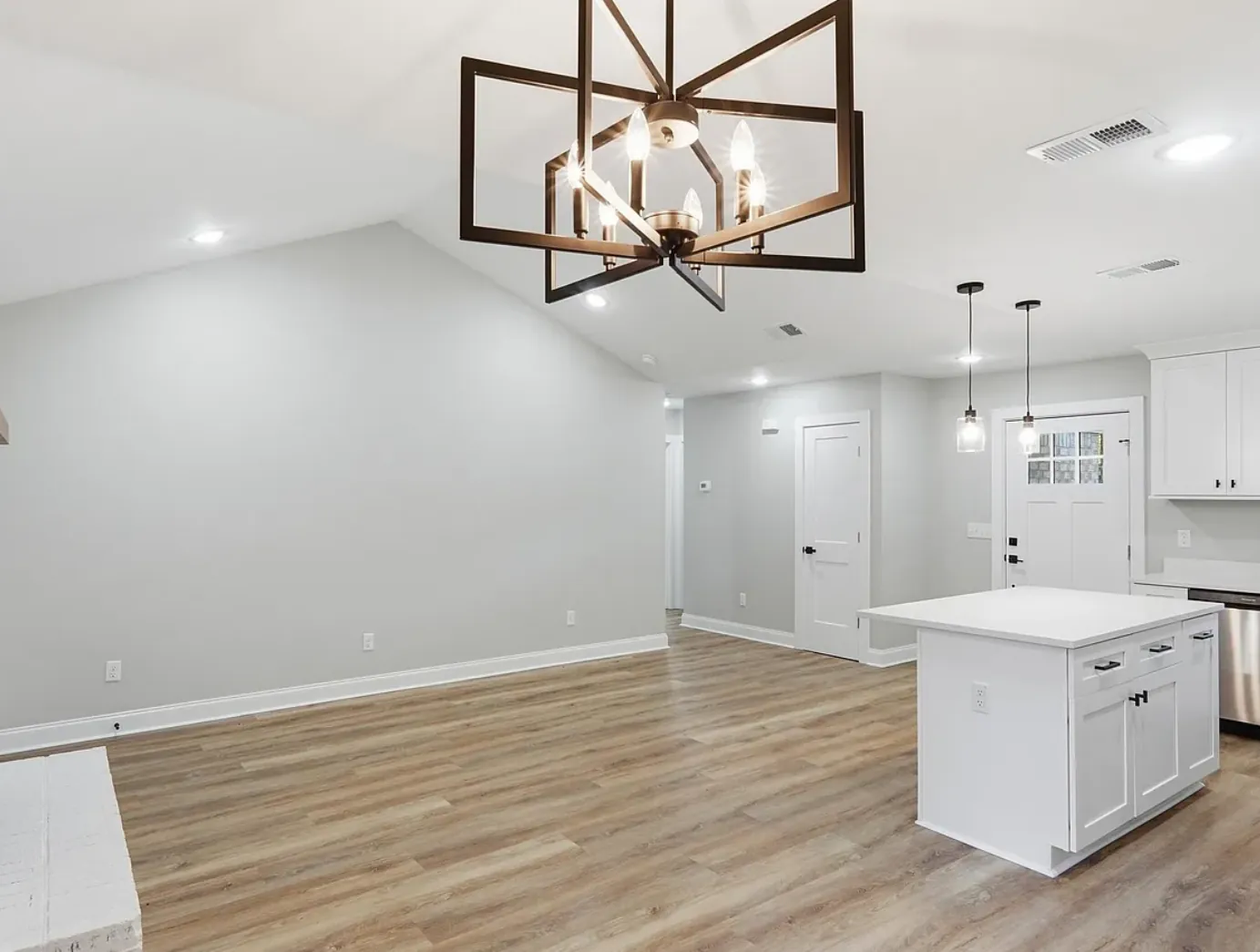 Renovated open living and kitchen area with vaulted ceiling by J&W Construction & Design